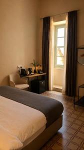 a hotel room with a bed and a desk and a window at Mulberry Suites by The LVH Collection in Valletta