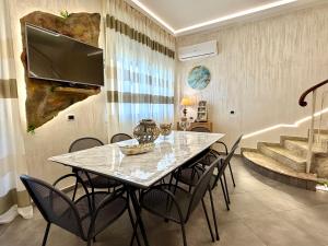 a dining room table with chairs and a television on a wall at Castello di Sabbia in Trabia