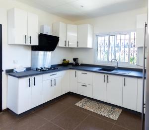a kitchen with white cabinets and a sink at Mne villa 3 chambres in Douala