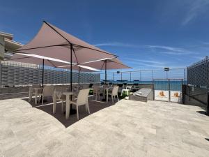 a patio with tables and chairs and an umbrella at Castello di Sabbia in Trabia