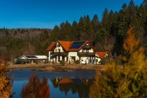 a house with a solar roof next to a lake at Biosfera Klingeis in Avrig
