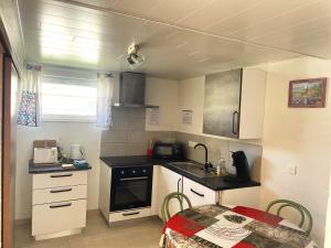 a small kitchen with white cabinets and a table at Gîte 'A deux pas du ciné' in Maîche