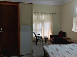 a bedroom with a bed and a chair and a window at Saurabh home stay in Dibrugarh
