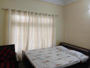 a bed in a bedroom with a window with curtains at Saurabh home stay in Dibrugarh
