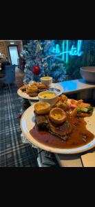 three plates of food on a counter with a christmas tree at Claremont Hotel in Alloa