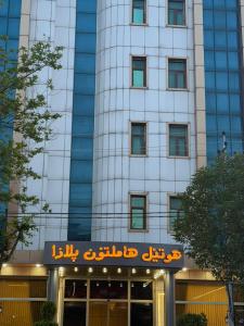 a tall building with a sign in front of it at Hamilton Plaza Hotel in Diyānah