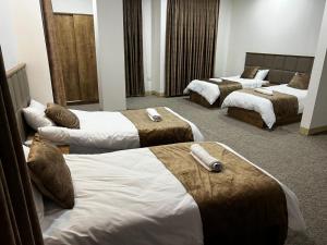 a hotel room with three beds with towels on them at Hamilton Plaza Hotel in Diyānah