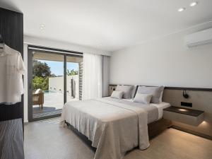 a white bedroom with a bed and a sliding glass door at Hesperian Luxury Villas with Private Heated Pools in Chania +50 photos