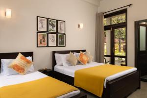 two beds with yellow and white sheets in a room at Divulgaha Gedara Boutique Hotel in Anuradhapura