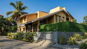 a yellow house with a fence and a palm tree at Rare Aura Villa in Dod Jāla