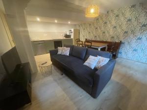 a living room with a blue couch and a kitchen at Chez Mamema in Barr