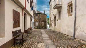 an empty alley with a bench in an alley between buildings at Albergue Mayor in Sarria