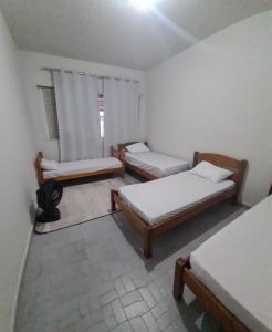 a room with three beds and a window at Beach Hostel do Japa in Ubatuba