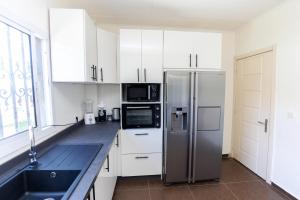 a kitchen with white cabinets and a stainless steel refrigerator at Mne villa 3 chambres in Douala +4 photos