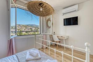 ein Schlafzimmer mit Bett, Schreibtisch und Fenster in der Unterkunft Hôtel Paradis in Bormes-les-Mimosas