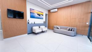 a lobby with two couches and a tv on a wall at Hotel Novo Sol in Petrolina
