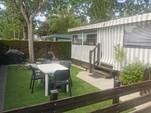 a patio with a table and chairs in a yard at Mobil-home cosy avec terrasse et jardin privatif in La Bernerie-en-Retz