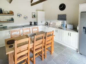 a kitchen with white cabinets and a wooden table and chairs at Cloggy Nook Tughall in Swinhoe