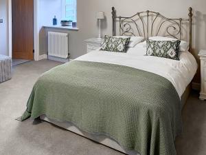 a bedroom with a large bed with a green blanket at Cloggy Nook Tughall in Swinhoe