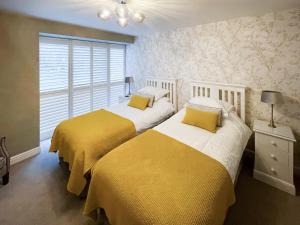 two beds in a bedroom with yellow and white at Cloggy Nook Tughall in Swinhoe +6 photos