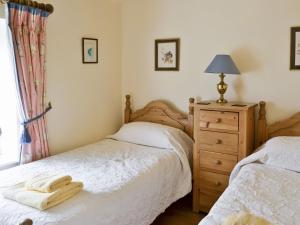 a bedroom with two beds and a dresser with a lamp at The Appleloft in Westleigh +8 photos
