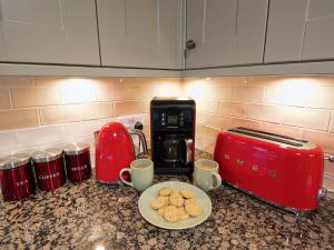 a counter top with a plate of cookies and coffee cups at Drummuie House in Golspie
