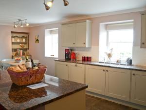 a kitchen with white cabinets and a basket on a counter at Drummuie House in Golspie