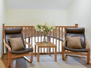 two chairs and a table with a vase of flowers at Tythe Barn in Froggatt