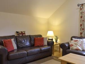 a living room with a leather couch and a chair at Tythe Barn in Froggatt