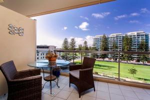 a balcony with a table and chairs and a large window at Glenelg Holiday Apartments-Pier in Adelaide
