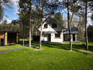 a white house with trees in the grass at Kropla Rosy 27 in Orchówek
