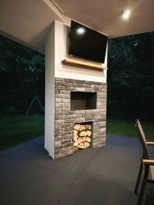 a stone fireplace with a tv on top of it at Kropla Rosy 27 in Orchówek
