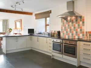 a kitchen with white cabinets and a stove top oven at Polmear Barn in Camelford
