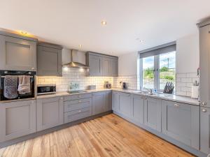 a large kitchen with gray cabinets and a large window at Ty Godro - Uk12745 in Acrefair