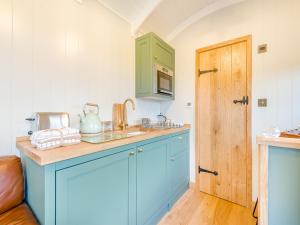 a kitchen with blue cabinets and a green door at Hut Uk42176 in Usk