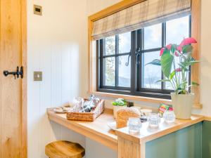 a kitchen counter with a window and a table with food at Hut Uk42176 in Usk