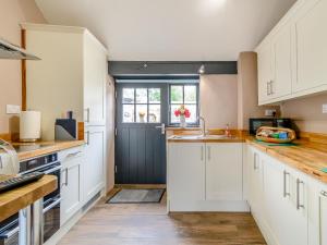 a kitchen with white cabinets and a black door at Stable Cottage in Pembroke +15 photos