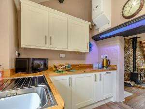 a kitchen with white cabinets and a sink and a clock at Stable Cottage in Pembroke