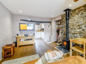 a living room with a fireplace and a stone wall at Stable Cottage in Pembroke
