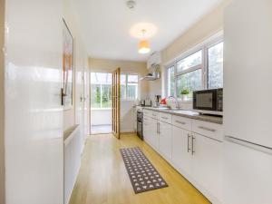 a kitchen with white cabinets and a sink and a microwave at Pine Cottage - Uk46874 in Hartland