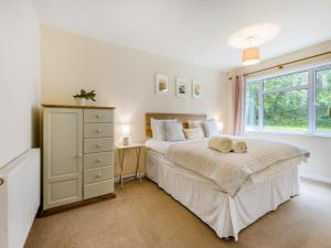 a bedroom with a bed with a dresser and a window at Pine Cottage - Uk46874 in Hartland +16 photos
