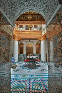 a room with a table and chairs on a mosaic floor at Riad Medina Unique in Fez