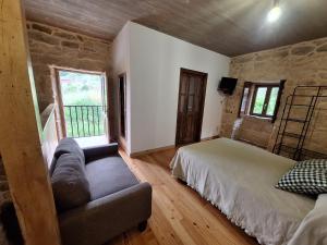 a bedroom with a bed and a couch and a window at Casa de mestre 2 in Freijo