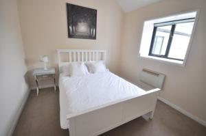 a white bedroom with a white bed and a window at Stable Cottage 2 in Sedghill