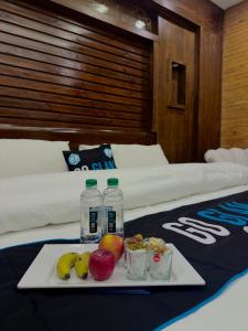 a tray with fruit and water bottles on a bed at Go Glam Hotels Murree in Murree