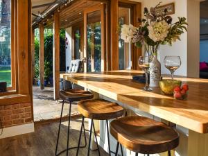 a kitchen with a large wooden counter with stools at Myrtle Cottage in Potter Heigham