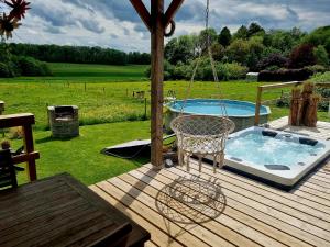 a swing on a deck next to a pool at Tiny housse serenity avec jacuzzi et piscine in Tinlot
