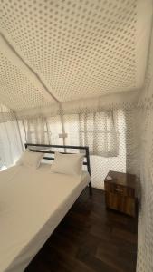a bedroom with a white bed with a wooden table at Sari Highlands chopta Offbeat campsite in Ukhimath