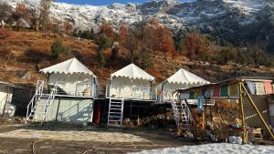a group of white tents in front of a mountain at Sari Highlands chopta Offbeat campsite in Ukhimath