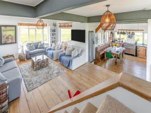 a living room with blue couches and a kitchen at Lower Hendra Cottage in Port Isaac